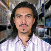 Greg Reis Unsmiling man with long dark hair and facial hair